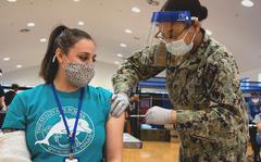 Andrea Hunt, a teacher's aide at Yokosuka Naval Base is vaccinated against COVID-19 byHospital Corpsman Janasia Spotson on March 19, 2021.