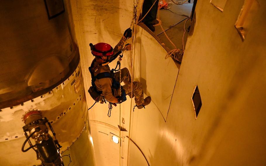 An airman rappels into a missile silo using a rope.