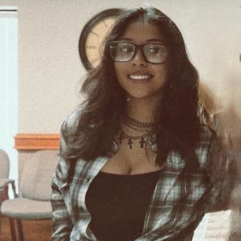 A woman in a flanel shirt and glasses.