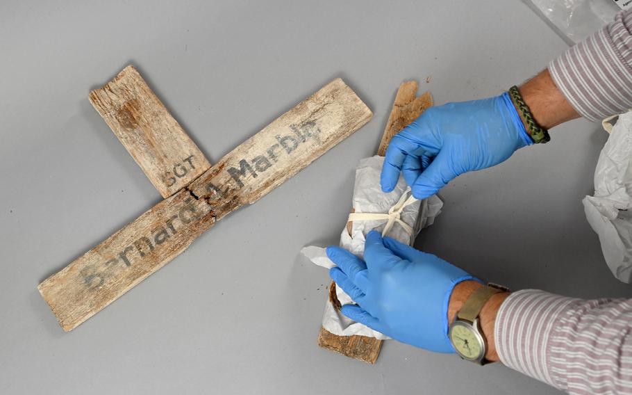 Owen L. Conner, curator for the National Museum of the Marine Corps, unwraps pieces of a wooden cross bearing the name of Sgt. Bernard A. Marble, 28, of Massachusetts, one of more than 1,000 Marines who died in the 1943 battle for Tarawa. 