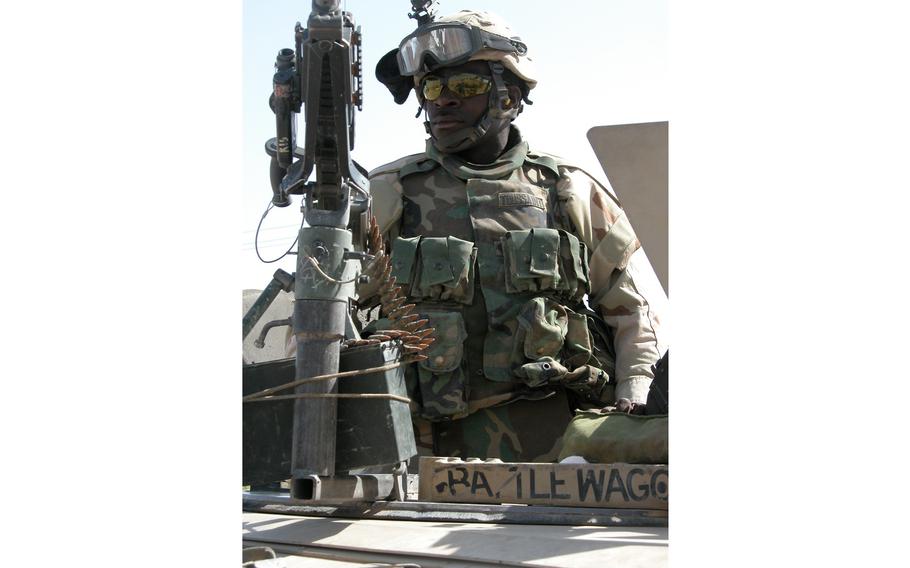 Pfc. Joe Strauch, of Company C, 4th Battalion, 31st Infantry Regiment waits atop an armored Humvee as his colleague talked to townspeople in Saba al Boor, Iraq.