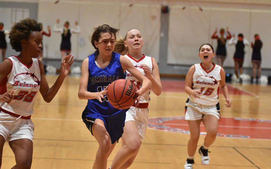 Rota's Jourdan Timmons tries to run through Aviano defenders Lania Burkes, from left, Ava Chambers and Maliyah Leyva during a fast break Friday, Dec. 9, 2022 in Aviano, Italy.