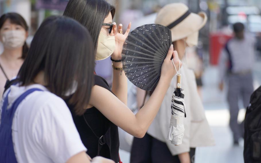 A woman fans herself in central Tokyo on June 28, 2022.   