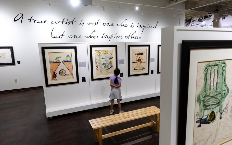A girl looks at Dalí paintings in a museum. 