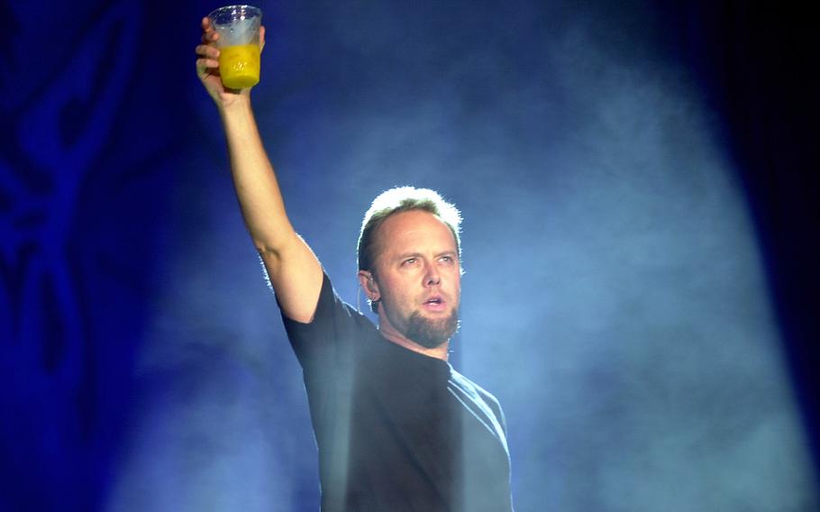 A man in a black T-shirt holds a cup high in the air.