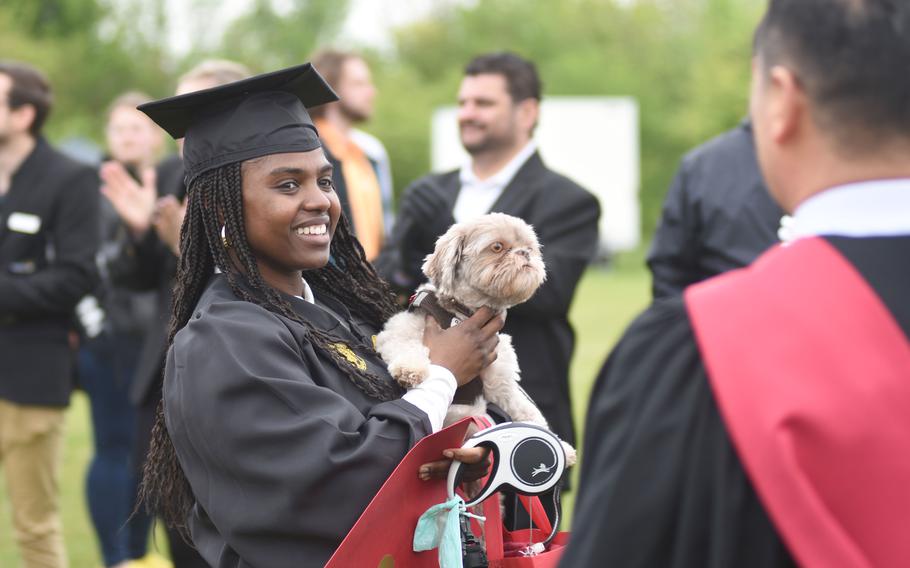 Army Staff Sgt.  Samcess Fofanah carries his dog, Loki, after graduating in Health Services Management in the Class of 2022 from Global Campus Europe at the University of Maryland on Saturday, April 30, 2022 in Obersuelzen, Germany.  Fofanah is assigned to the 30th Medical Brigade in Sembach, Germany.