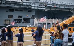 Friends and family members wave goodbye as the aircraft carrier USS Ronald Reagan sets out for patrol from Yokosuka Naval Base, Japan, Friday, May 20, 2022.