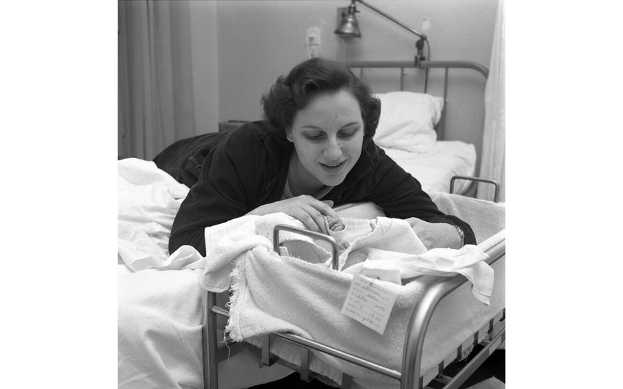 A happy mother looks at her newborn baby as it lies in its crib in the maternity ward at the 97th U.S. Army Hospital in Frankfurt. 