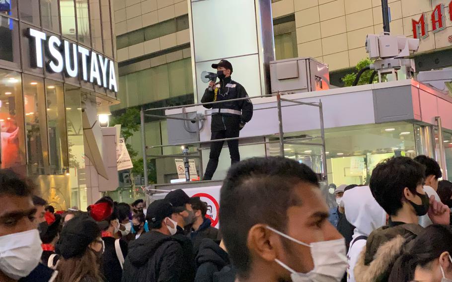 Japanese police keep crowds moving near the popular scramble crossing in Tokyo's Shibuya ward, Oct. 31, 2021.