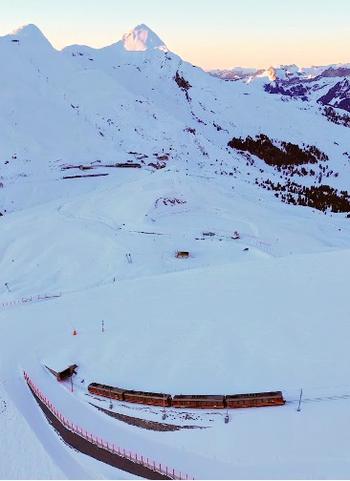 Jungfraubahn from above with the sun peeking out from behind the snowy mountain