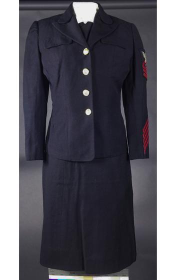 A dark blue uniform with a blazer and skirt seen against a gray background.