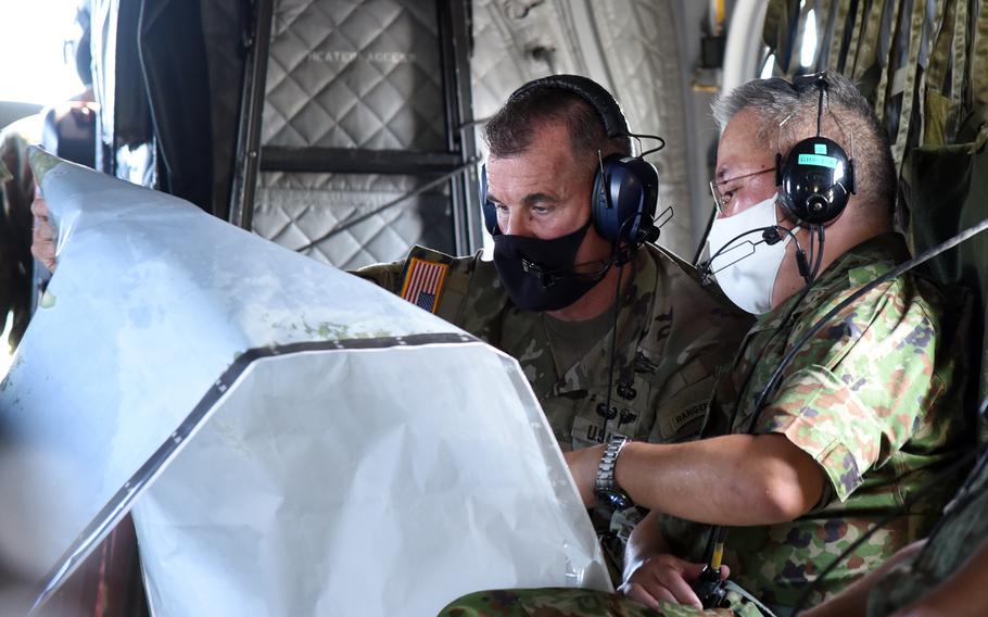 The commander of U.S. Army Pacific, Gen. Charles Flynn, and the head of the Japan Ground Self-Defense Force, Gen. Yoshihide Yoshida, sit inside a Kawasaki OH-1 helicopter on Amami Oshima, Japan, Thursday, Sept. 8, 2022.