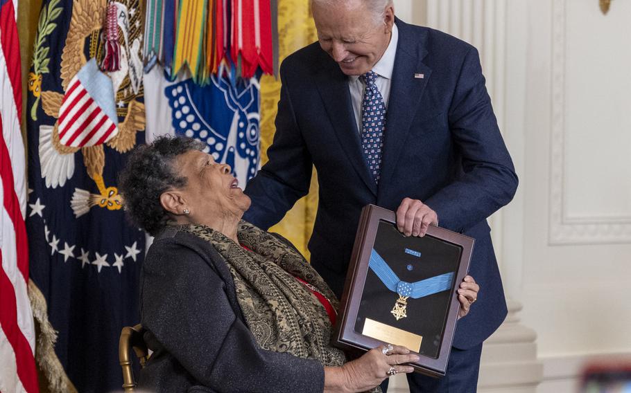 Joe Biden presents a framed Medal of Honor to a seated elderly woman, awarded posthumously to her brother.