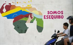 FILE - A youth drives a motorcycle in front of a mural of a map of Venezuela with the Essequibo territory, a swath of land administered and controlled by Guyana but claimed by Venezuela, in the 23 de Enero neighborhood of Caracas, Venezuela, Dec. 11, 2023. (AP Photo/Matias Delacroix, File)