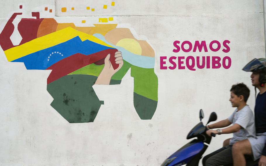A youth drives a motorcycle in front of a mural of a map of Venezuela with the Essequibo territory, a swath of land administered and controlled by Guyana but claimed by Venezuela, in the 23 de Enero neighborhood of Caracas, Venezuela, Dec. 11, 2023.