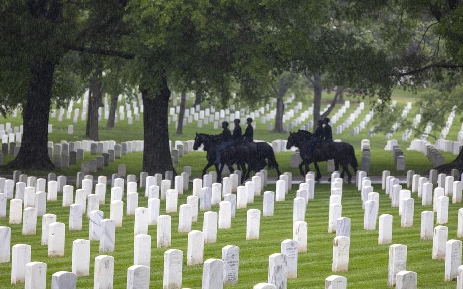 Soldiers ride horses among the gravestones at Arlington.
