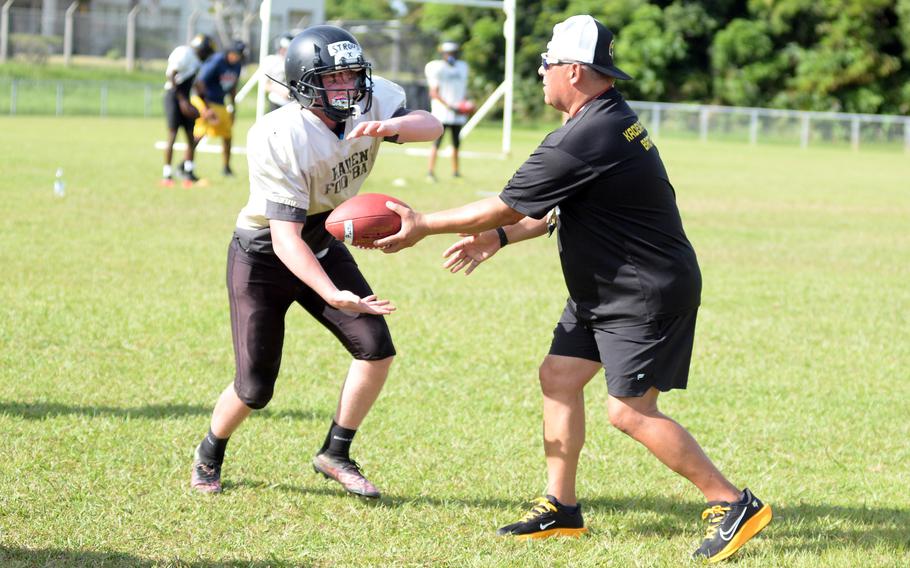 Kadena's Matthew Stroud takes a handoff from assistant coach Frank Macias during Monday's practice.