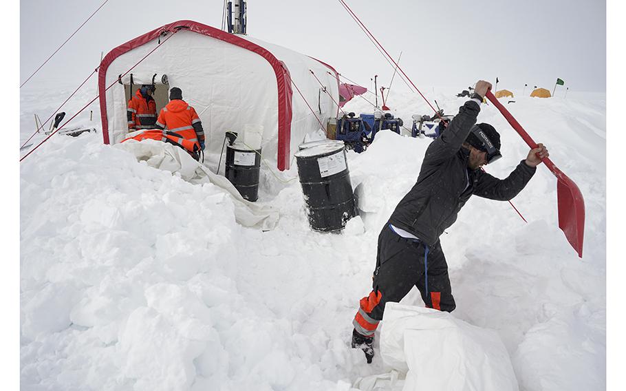 Driller Forest Rubin Harmon clears snow outside the ASIG drill tent. 