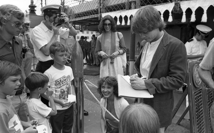 Mark Hamill  signs autographs at Yokosuka Naval Base. Hamill toured the destroyer with his girlfriend Marilou York (crouching) and his agent Nancy Hutson (behind him), patiently scrawling his signature many times for a mob of adoring kids, some of whom wore “Star Wars” T-shirts.