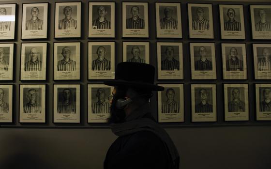 An orthodox Jew walks past the portraits of victims at the former Nazi German concentration and extermination camp Auschwitz-Birkenau in Oswiecim, Poland, Thursday, Jan. 26, 2023. Survivors of Auschwitz-Birkenau are gathering to commemorate the 78th anniversary of the liberation of the Nazi German death camp in the final months of World War II, amid horror that yet another war has shattered the peace in Europe. The camp was liberated by Soviet troops on Jan. 27, 1945. (AP Photo/Michal Dyjuk)