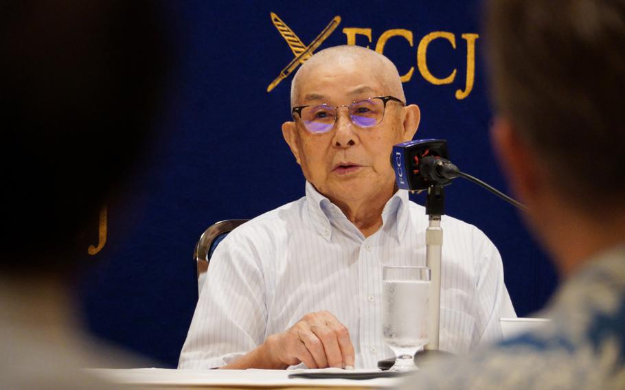 An older man speaks into a microphone.