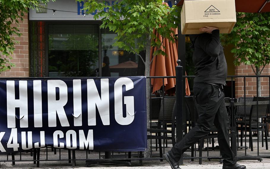 A man walks past a “now hiring” sign posted outside of a restaurant in Arlington, Virginia on June 3, 2022. 