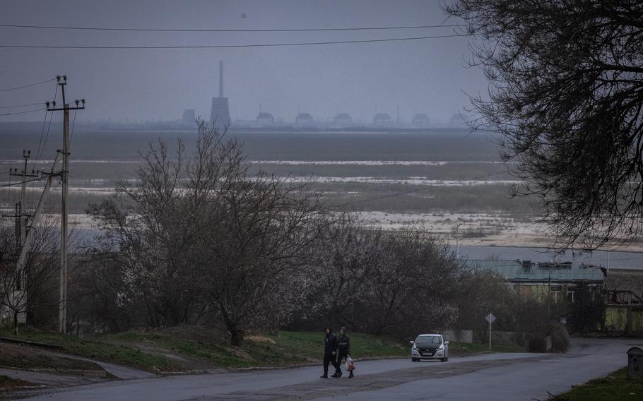 The towers of the Zaporizhzhia nuclear power plant under gray skies across the river.