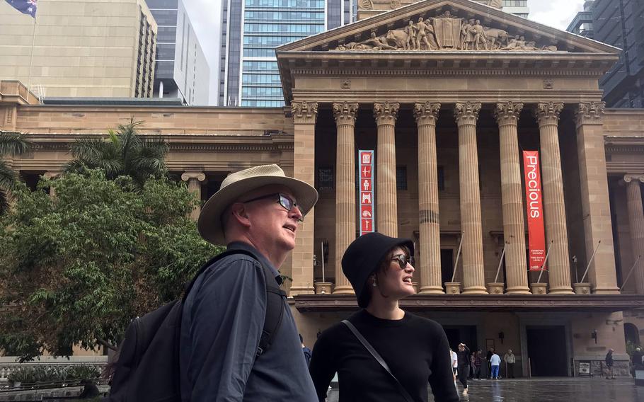 Two tour guides pass a museum in Brisbane, Australia.