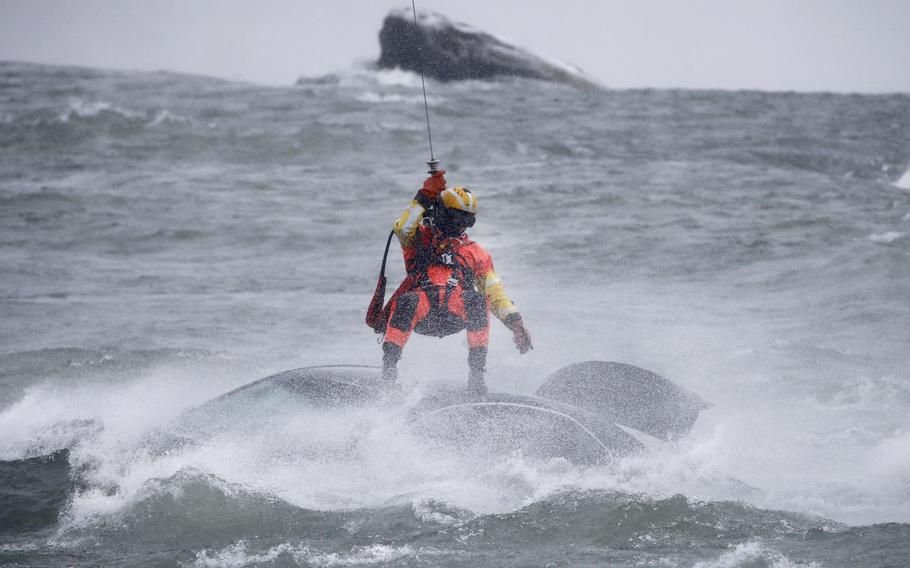 Coast Guard rescue swimmer Derrian Duryea is lowered from a hovering helicopter to pull a body from a submerged vehicle stuck in rushing rapids just yards from the brink of American Falls, one of three waterfalls that make up Niagara Falls, on Wednesday, Dec. 8, 2021, in Niagara Falls, N.Y.