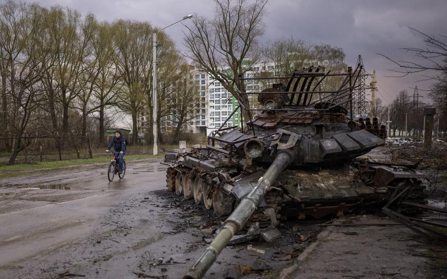 A man rides his bicycle next to a destroyed Russian tank in Chernihiv, Ukraine, on Thursday, April 21, 2022. 