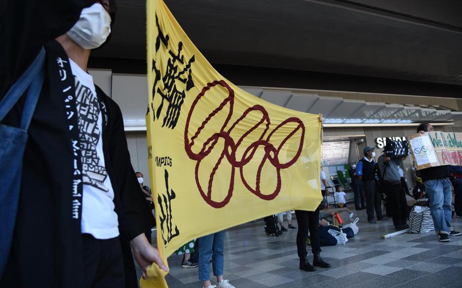 Protesters hold up a banner and shout near National Stadium just hours before the official start of the Tokyo Olympics, Friday, June 23, 2021. 