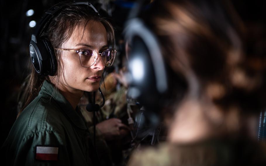 Polish air force nurse 2nd Lt. Magdalena Gawlowska-Baran listens to U.S. Air Force Maj. Melissa Proctor of the 86th Medical Squadron during a flight June 6, 2023, aboard a C-130 Hercules. Medical technicians collaborated on the training flight, which went from Ramstein Air Base, Germany, to Romania and back.