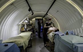 Medics treat shrapnel wounds on a soldier injured by a grenade dropped from a Russian drone, inside Ukraine’s first underground field hospital. Reinforced with metal structures — nicknamed “barrels” by medics — the facility allows surgeries some 20 feet underground. MUST CREDIT: Serhiy Morgunov/For The Washington Post