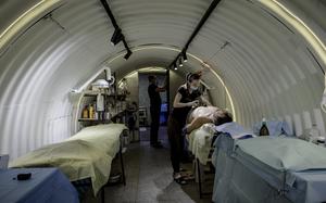 Medics treat shrapnel wounds on a soldier injured by a grenade dropped from a Russian drone, inside Ukraine’s first underground field hospital. Reinforced with metal structures — nicknamed “barrels” by medics — the facility allows surgeries some 20 feet underground. MUST CREDIT: Serhiy Morgunov/For The Washington Post