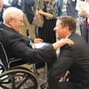 McPherson in a wheelchair talks with Adams, who is kneeling in front of him.