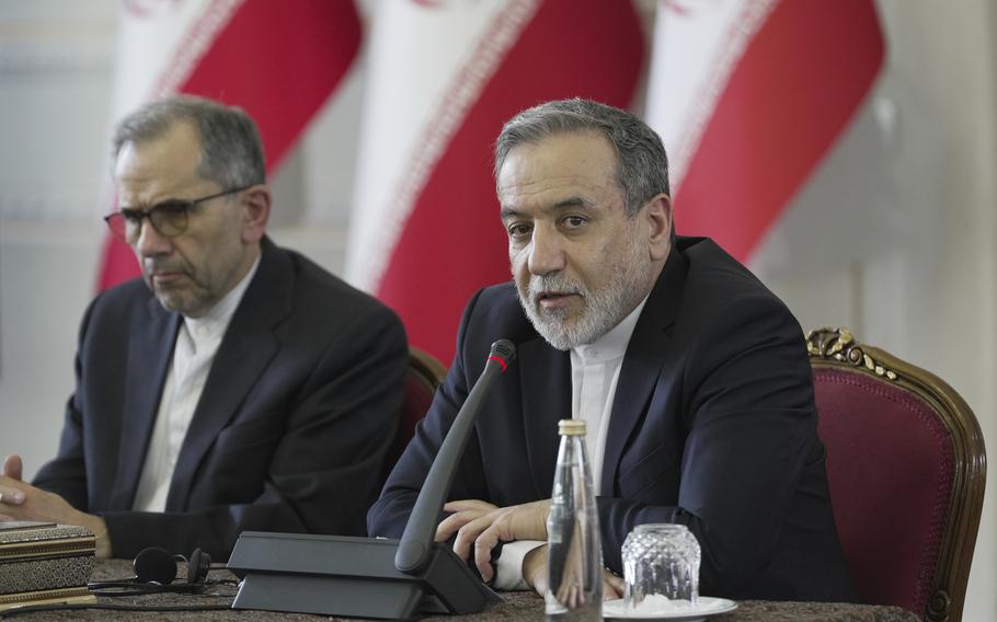 Two men in suits seated at a conference table.