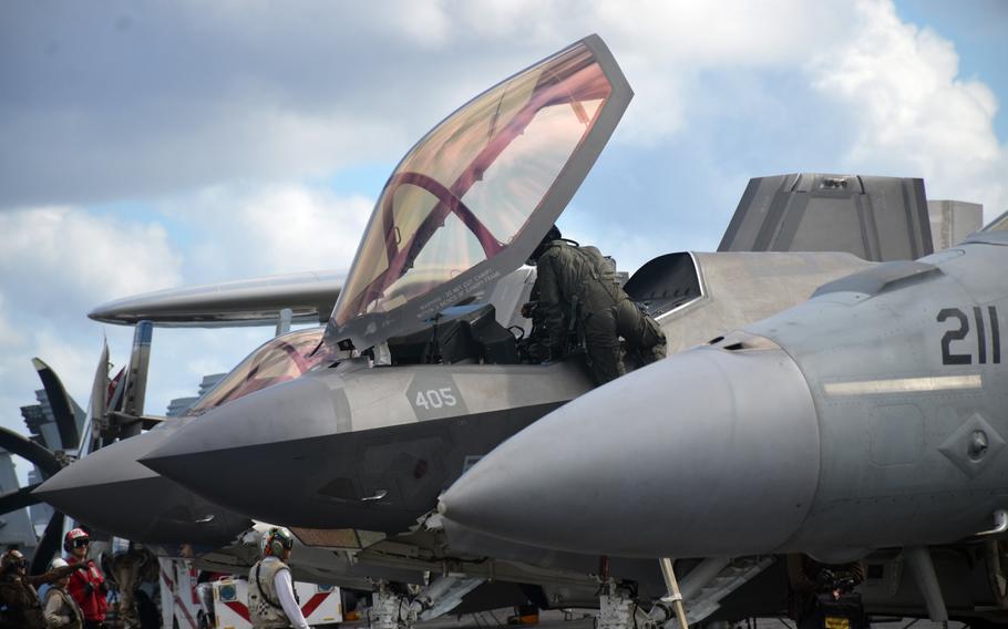 A Navy pilot climbs out of his F-35C Lightning II fighter jet aboard the aircraft carrier USS Carl Vinson in the Philippine Sea, Tuesday, Nov. 30, 2021.