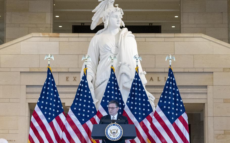 Mike Johnson stands and speaks from a podium with American flags behind him.