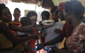 Women scuffle for plates of food for their children at a shelter for families displaced by gang violence, in Port-au-Prince, Haiti, Friday, March 22, 2024. (AP Photo/Odelyn Joseph)