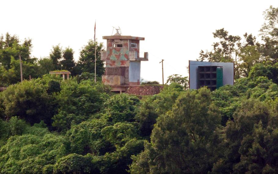 A view of a guard post positioned on elevated ground among dense green vegetation and trees. 