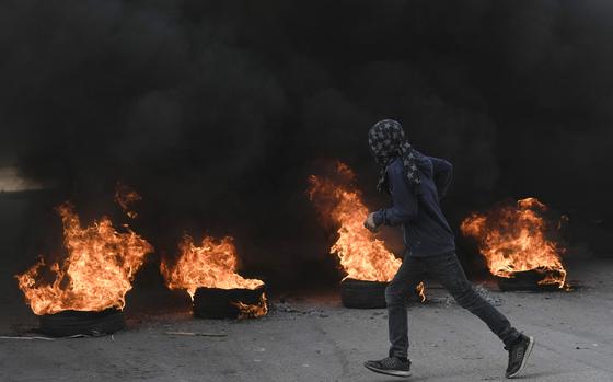 A masked Palestinian demonstrator burns tires in a protest against a deadly Israeli army raid at Aida Refugee camp, in the West Bank city of Bethlehem, Thursday, Jan. 26, 2023. During the raid in the West Bank town of Jenin, Israeli forces killed at least nine Palestinians, including a 60-year-old woman, and wounded several others, Palestinian health officials said, in one of the deadliest days of fighting in years. The Israeli military said it was conducting an operation to arrest militants when a gun battle erupted. (AP Photo/Mahmoud Illean)