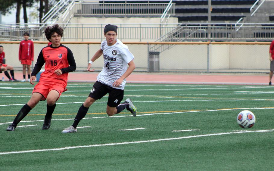 Nile C. Kinnick’s Brian Correa and Humphreys’ Tristan Michel turn to chase the ball during Monday’s boys Division I soccer tournament match. The Red Devils won 3-1.