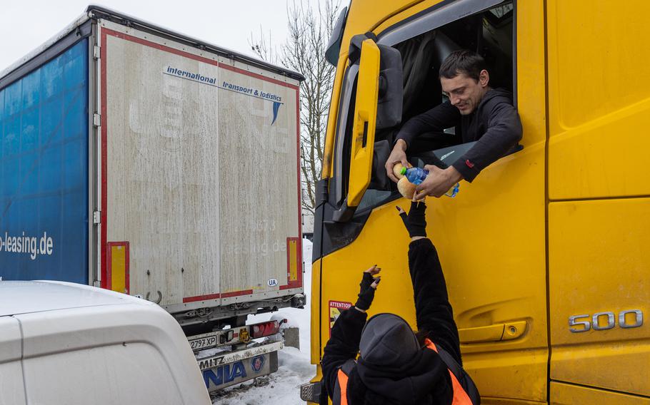 A volunteer provides food to a Ukrainian truck driver, in the parking lot near the Korczowa Polish-Ukrainian border crossing, on Dec. 5, 2023. Truck drivers have been stranded by a blockade that has caused disruption. Truckers have been stuck in Korczowa, one of the crossings blocked by protesting Polish hauliers who complain about what they say is unfair competition from Ukrainian companies.