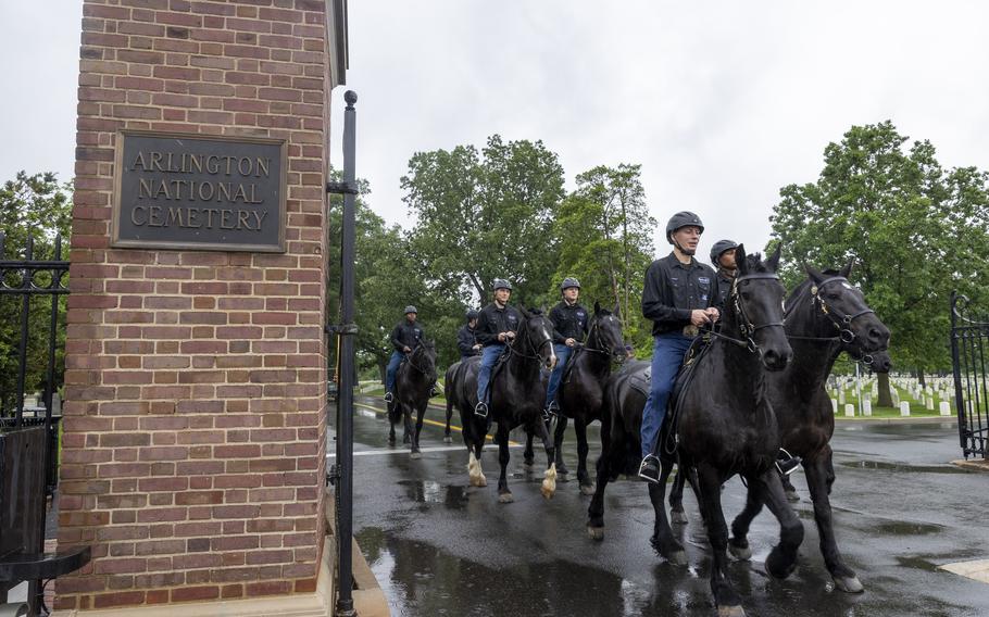 Soldiers ride their horses out of the Arlington Cemetery gate.