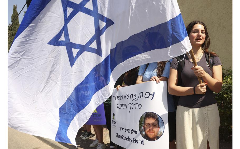Mourners hold signs outside the cemetery hosting the funeral of Israeli-American Elan Ganeles, on March 1, 2023, in Raanana. 