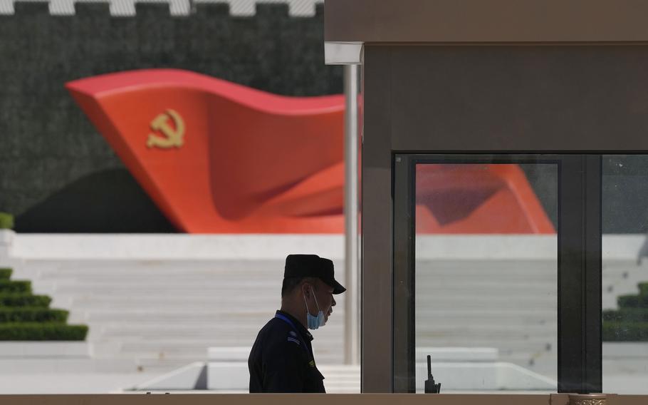 A security guard stands near a sculpture of the Chinese Communist Party flag at the Museum of the Communist Party of China on May 26, 2022, in Beijing.