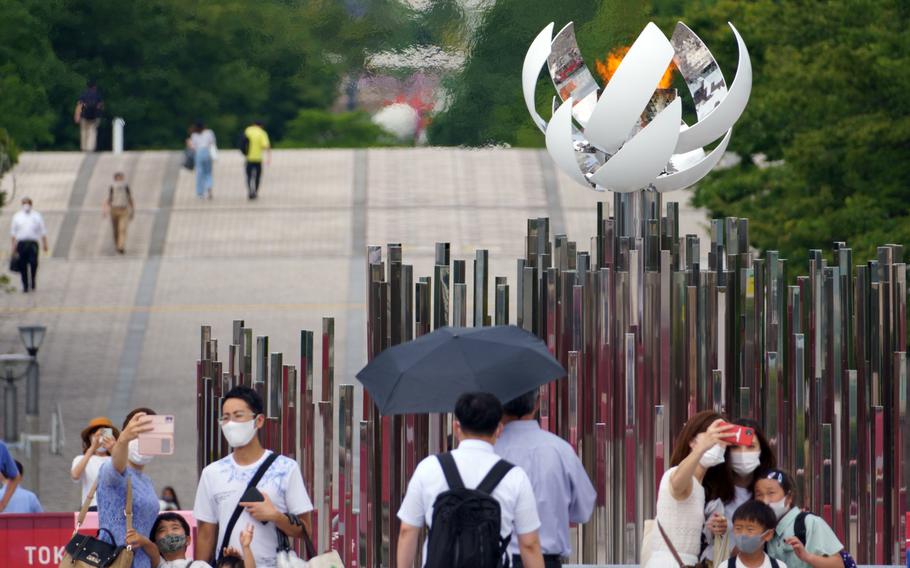 People pose with the Olympic cauldron in Ariake, Tokyo, July 30, 2021. 