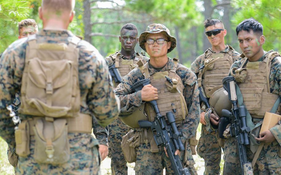 Marine infantry students listen to their combat instructor’s feedback after conducting an ambush during training at Camp Lejeune, N.C., on Aug. 27, 2021. The students were practicing an ambush during an initial infantry training pilot program meant to drastically change the way the Corps trains its infantrymen. The pilot program expands infantry training from nine to 14 weeks and places Marines in 14-person squads under a single instructor.