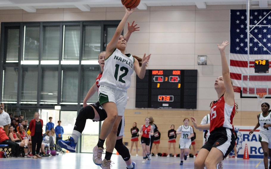 Naples’ Anais Navidad gets past AOSR’s Clara Clayton as she heads to the basket as Laila Lester waits to defend in the Division II championship game at the DODEA-Europe basketball finals in Ramstein, Germany, Feb. 18, 2023. AOSR defeated Naples 26-25 to take the title.