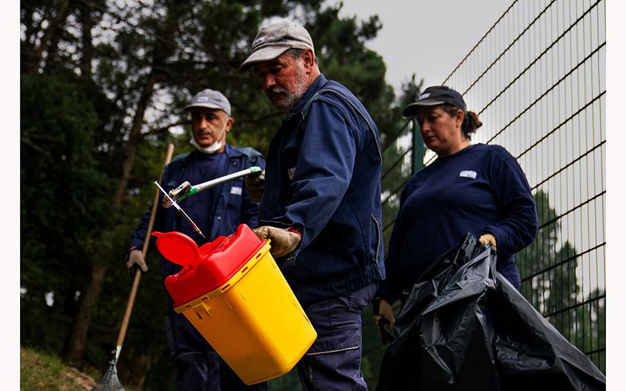 Municipal workers dispose of a used syringe at the Mata da Pasteleira park in Porto. 